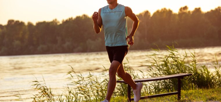 young-athletic-man-working-out-training-listening-music-riverside-outdoors